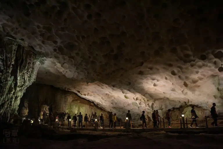 Silhouetted people walking inside illuminated cave.